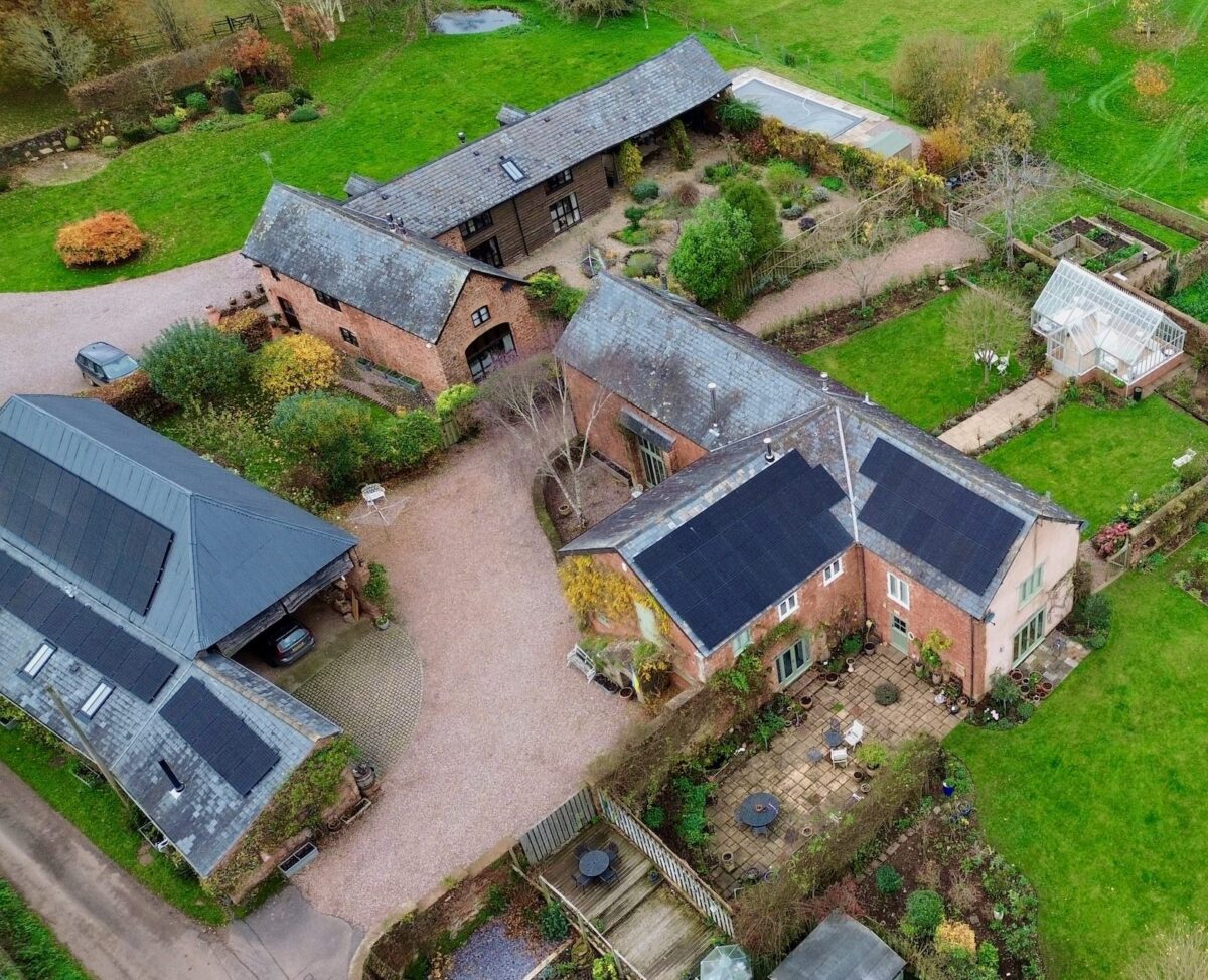 An aerial photo of solar panels on a house and barn complex.